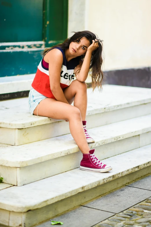 a woman is sitting on some steps with her hand in her hair