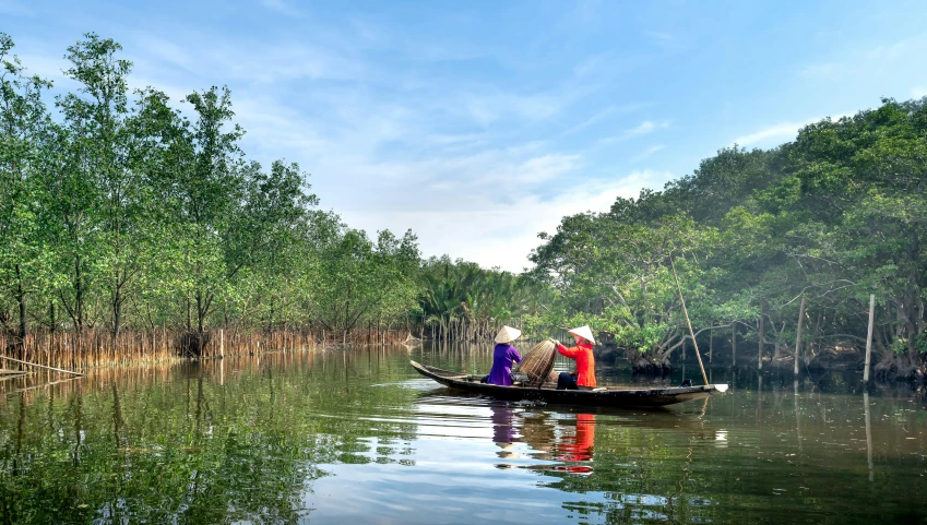 two people riding in a small boat down the river