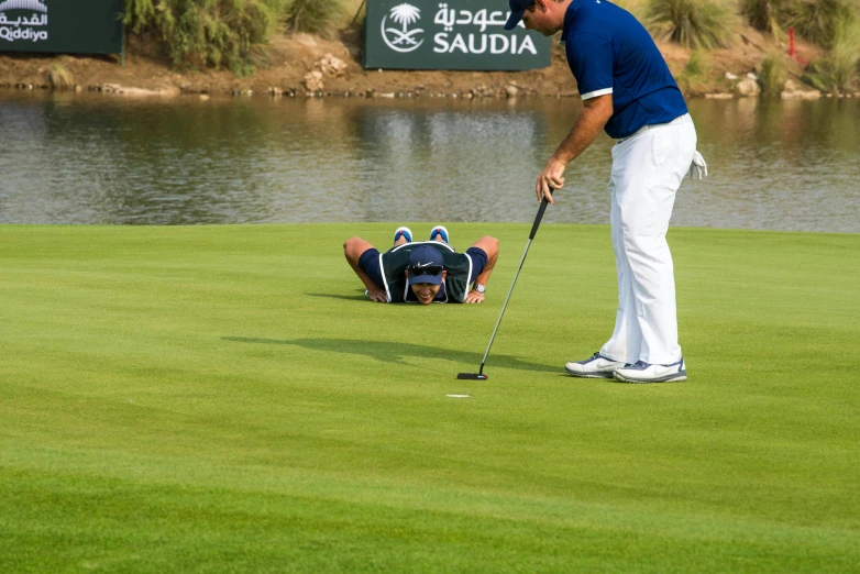 a golf player laying on the green after falling to the ground