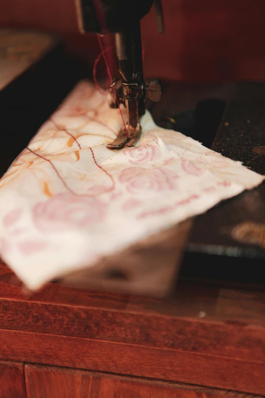 a machine stitches the fabric onto a piece of paper