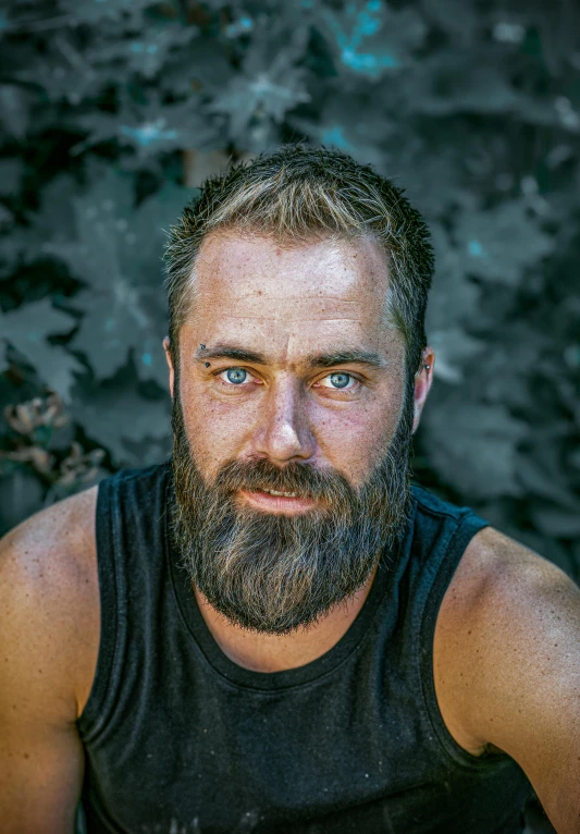 a man with a beard in front of black rock