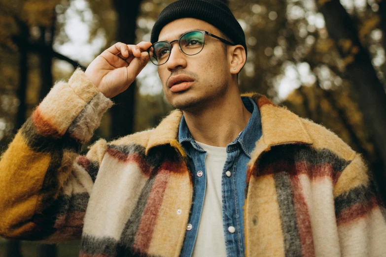 a young man wearing glasses and a plaid jacket