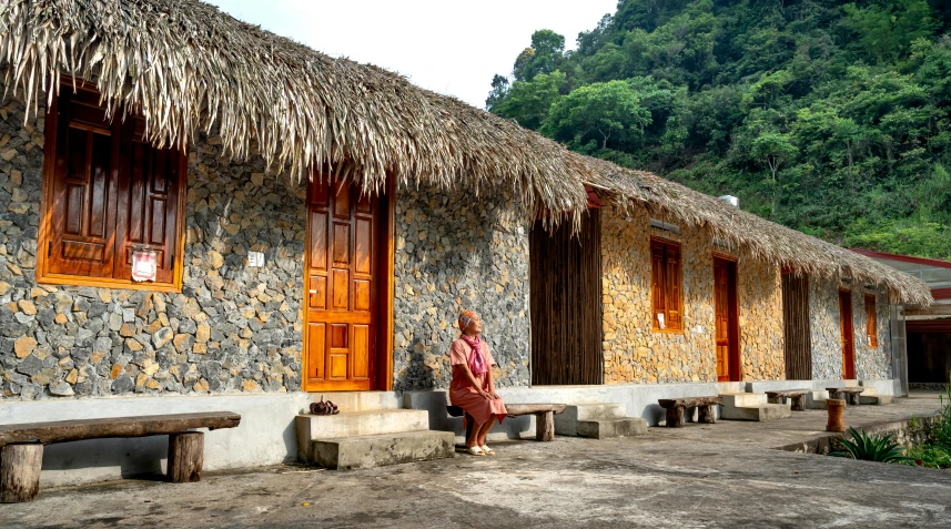 a small brick building with several windows and a woman standing in front of it