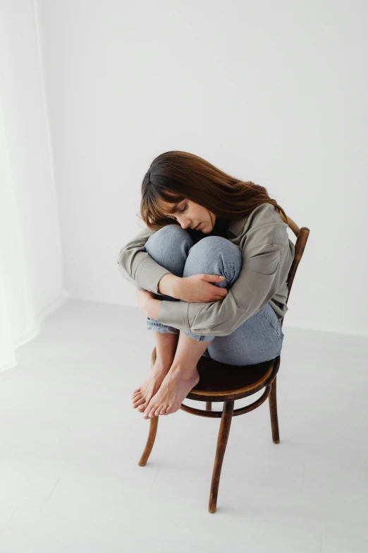 a woman hugs another woman while sitting on a chair