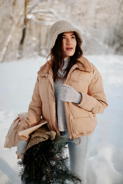 a woman holding a small fir tree in winter time