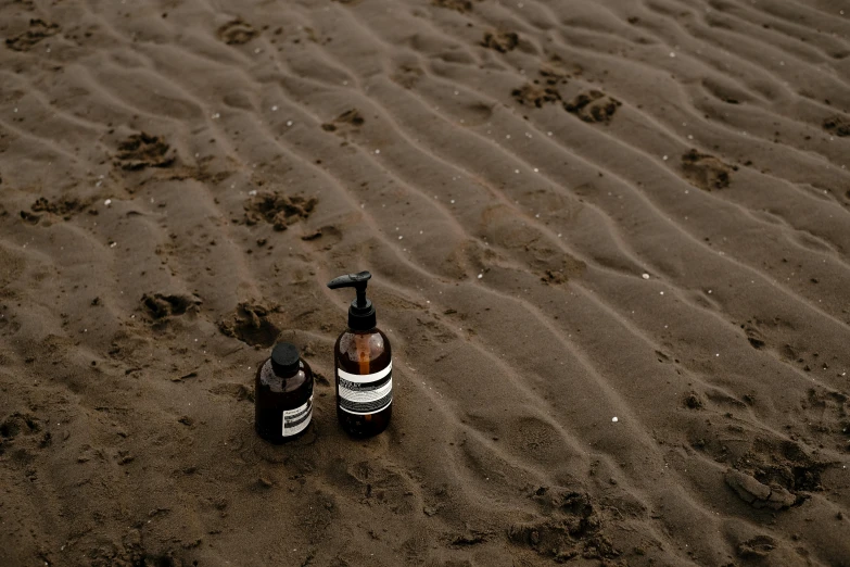 a bottle and a small pump sitting on the beach