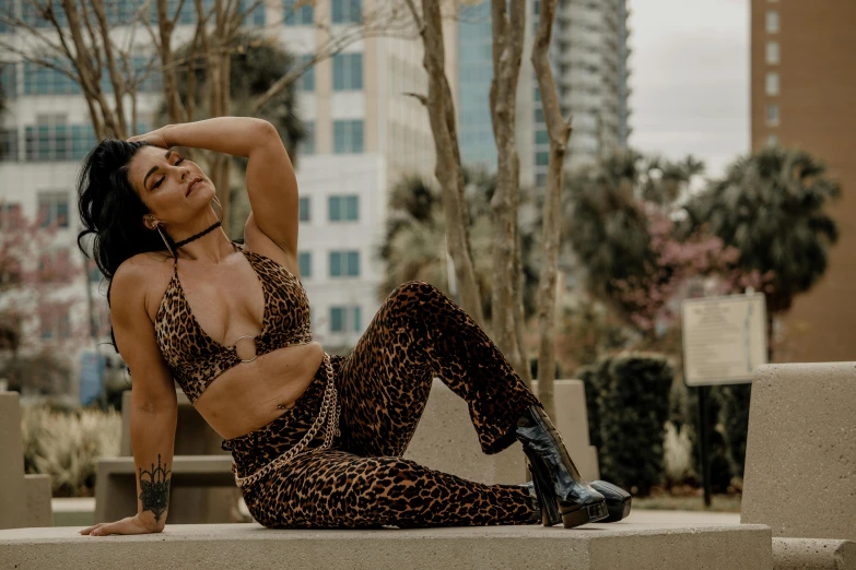 a woman sitting in a leopard print outfit on the cement ground