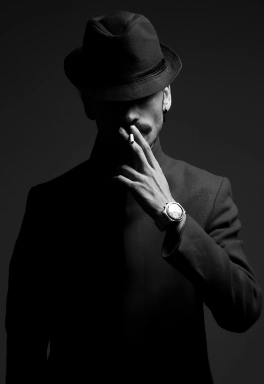 black and white po of a man in a suit, jacket, hat, and watch