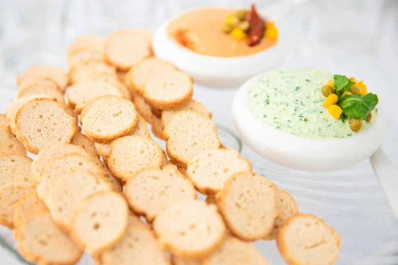 food sits next to a bowl with dip and bread