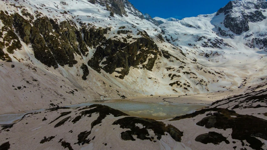 a small lake is in the middle of some snow covered mountains