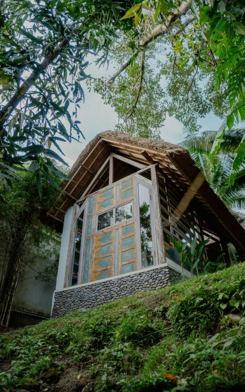 small house on top of green hill surrounded by trees