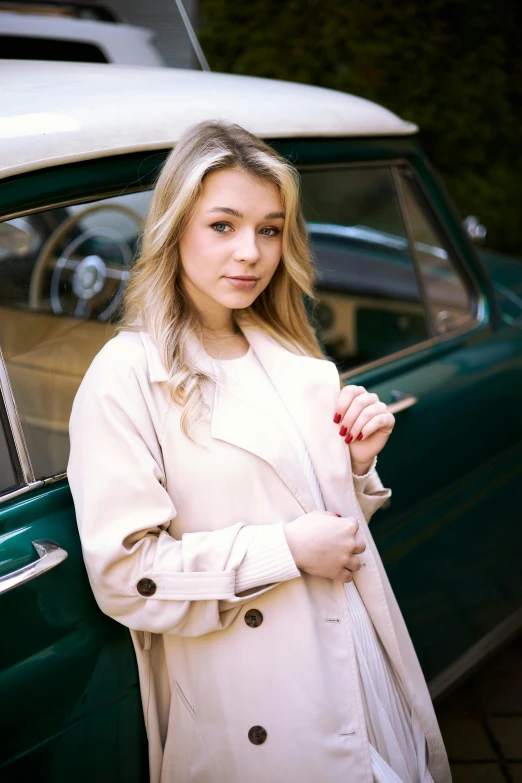 a pretty young blond woman standing next to a car