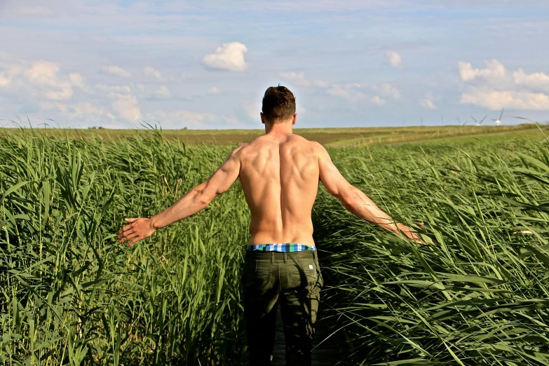 a young man is walking in tall green grass