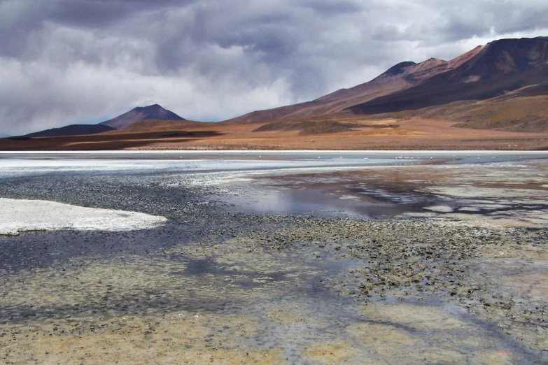 a view of some mountains by some ice in the water