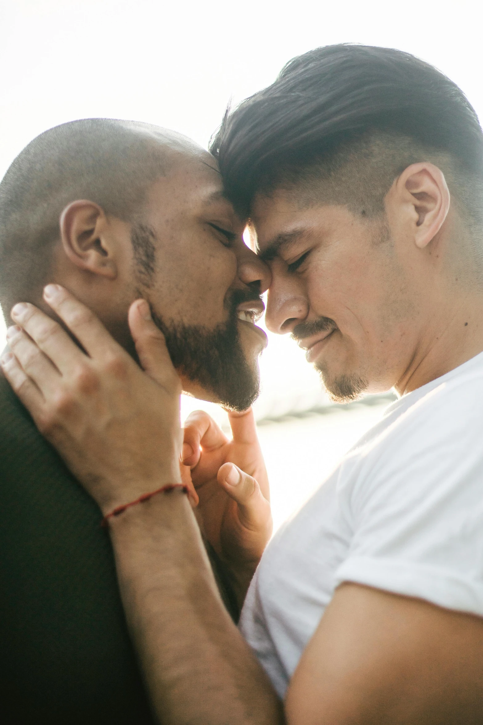 two men one with his face close to the other and kissing