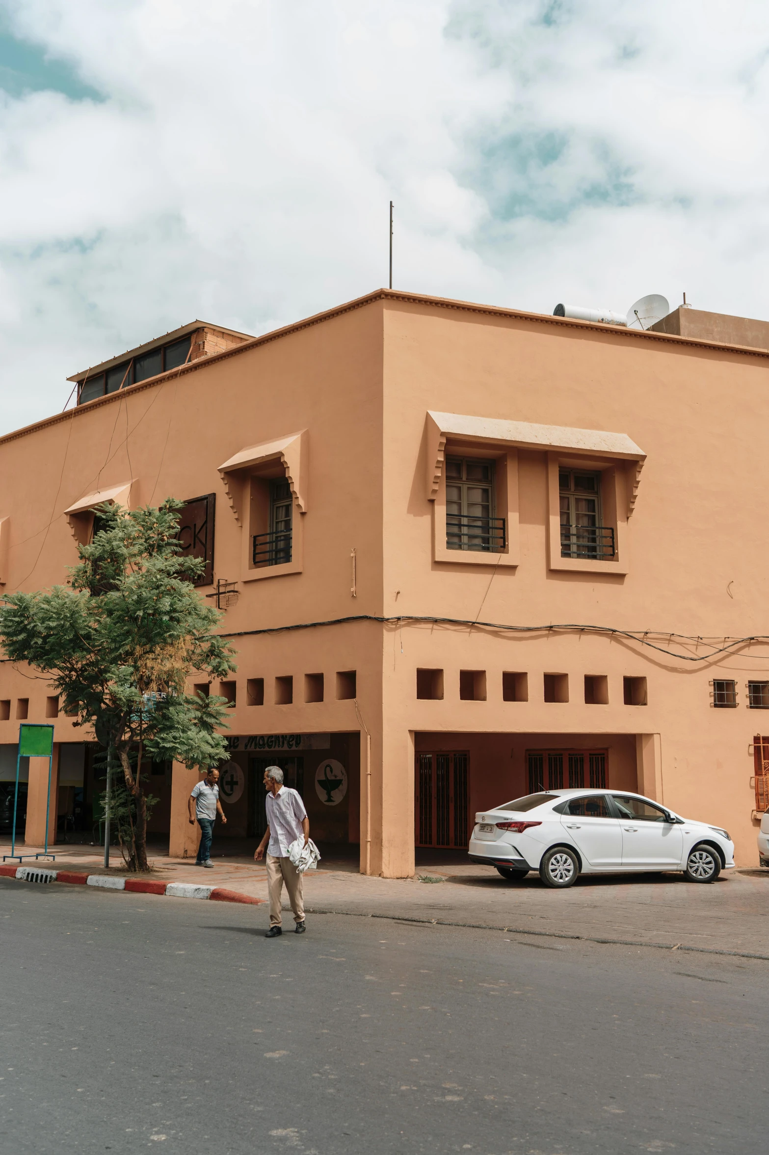 a building with cars parked in front of it and people walking around