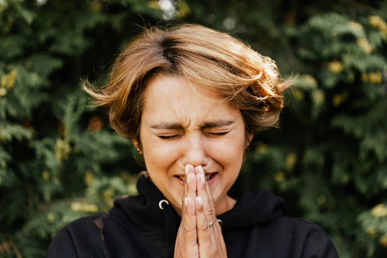 a woman is making a funny face while standing by some trees