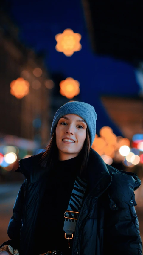 a woman in a hat standing on the street at night