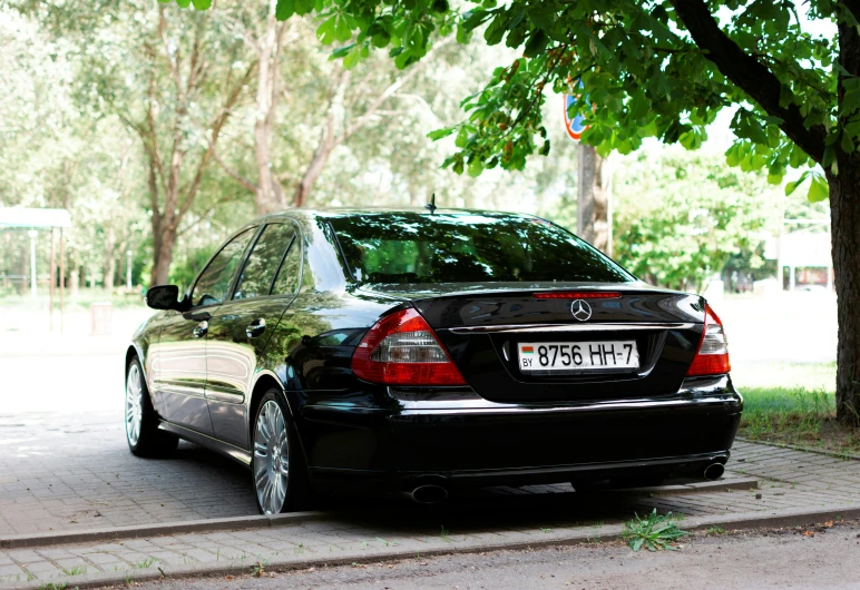 a black car parked on the sidewalk of a park