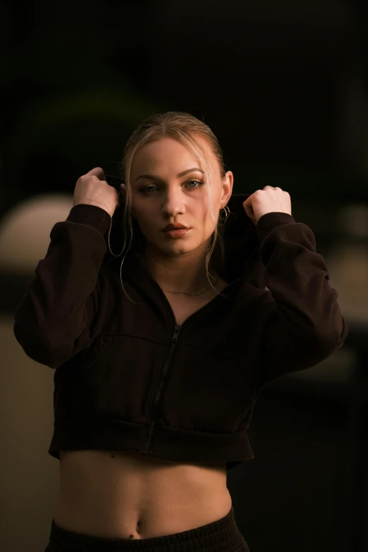 a girl in black hoodie holding onto her hair