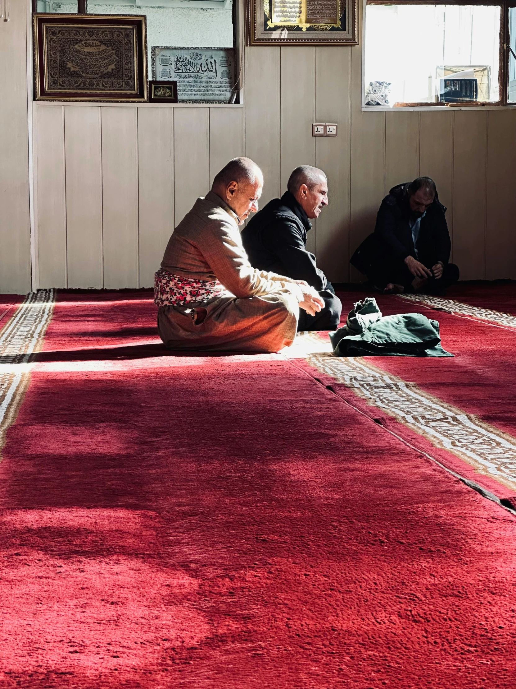 two men sitting on the floor and one is doing a prayer