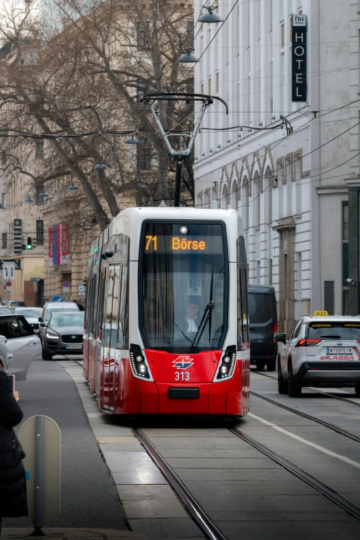 red and white commuter train coming down tracks in urban setting