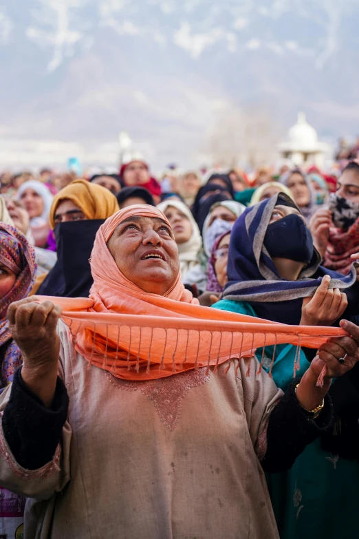 a woman holding up an orange object in front of a group of people