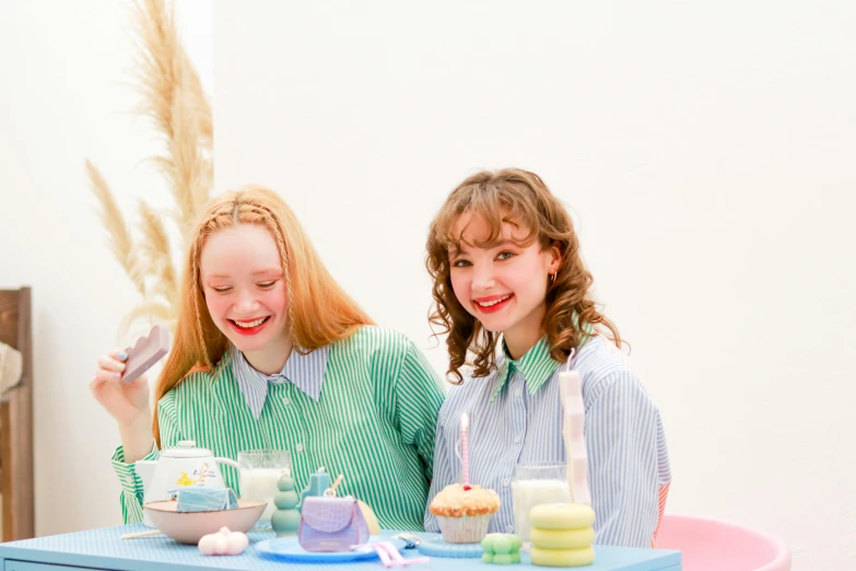 two girls at a cake table eating desserts