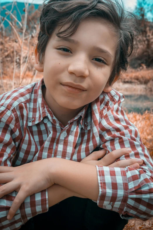 an adorable little boy sitting on a wooden bench with his arms crossed