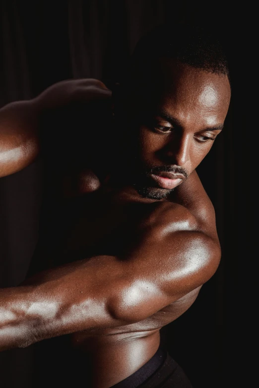 an athletic man poses in the dark for a picture