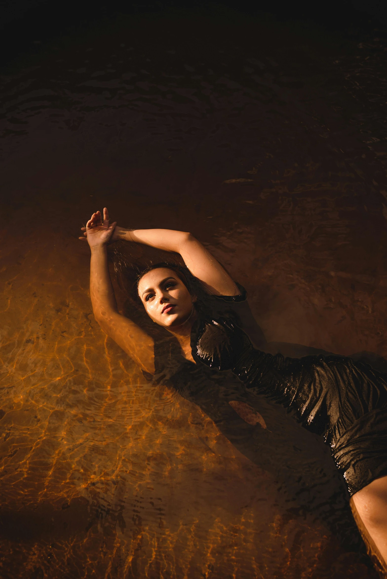 a woman wearing a black dress and posing in the water