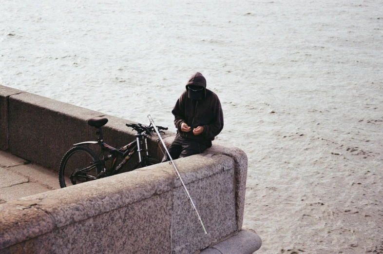 a man sitting on a concrete wall next to a bike