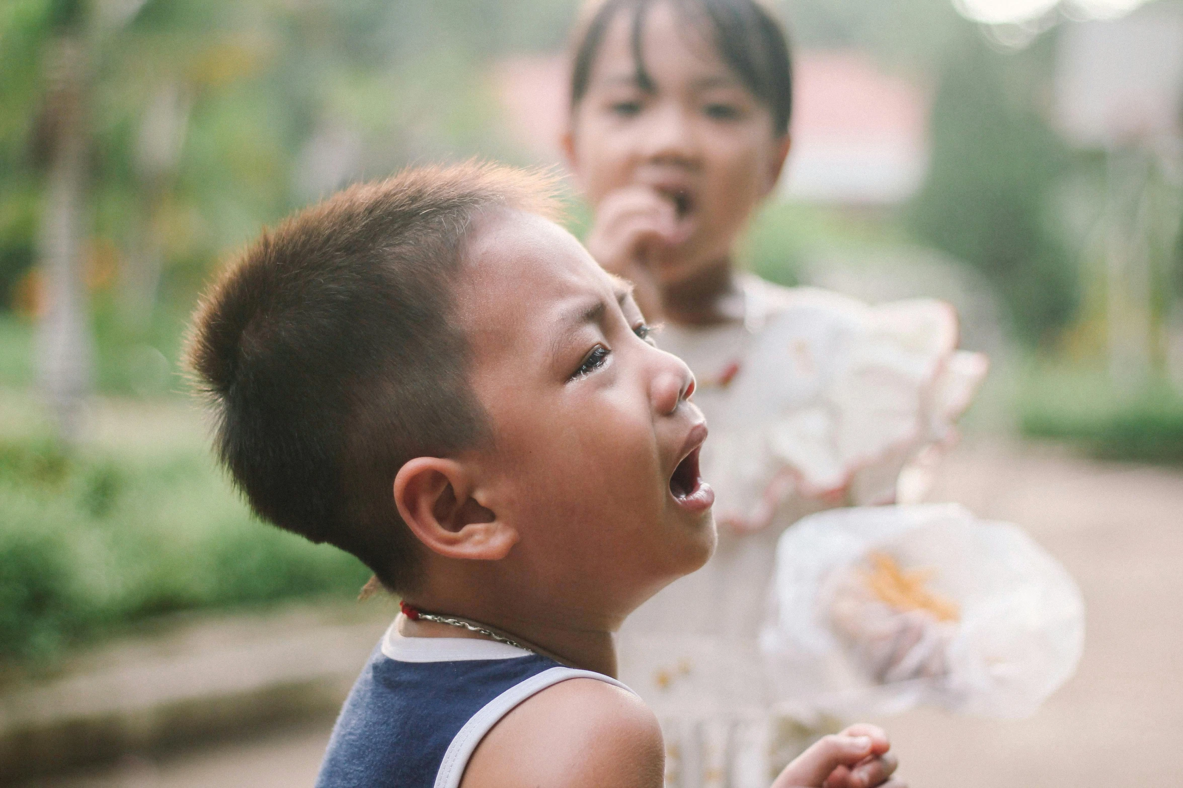 two small children stand outside in the rain