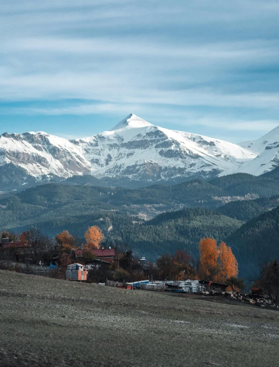 snow covered mountains, houses and cars in the foreground