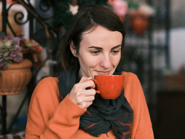 a woman sitting down drinking a cup of coffee