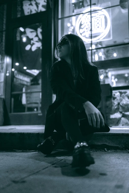 a person is sitting on a ledge outside of the store at night