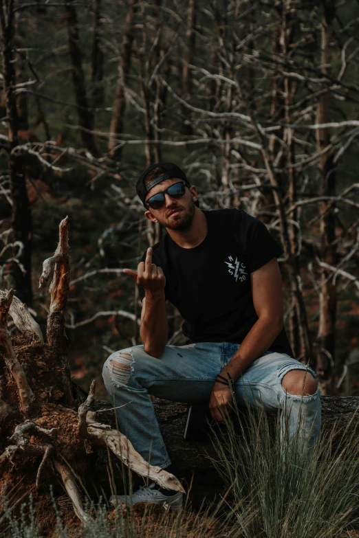 a young man poses for a po near a tree trunk