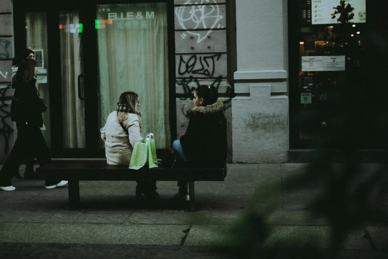 a woman sitting on a park bench next to a store front