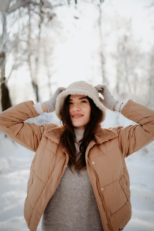 a woman poses in the snow wearing a winter coat