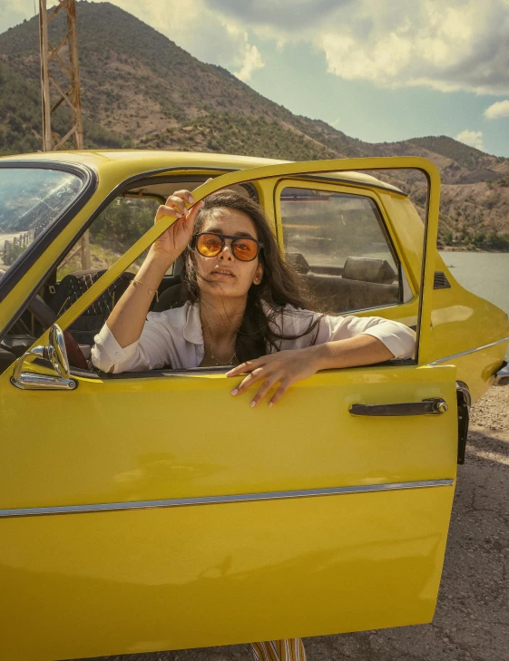 a woman in a yellow car wearing sunglasses