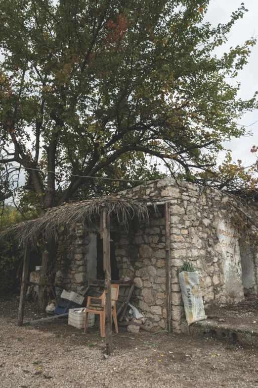 a stone and grass hut with two chairs