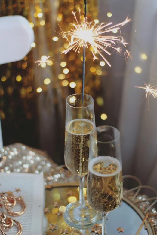two champagne flutes in front of a firework display