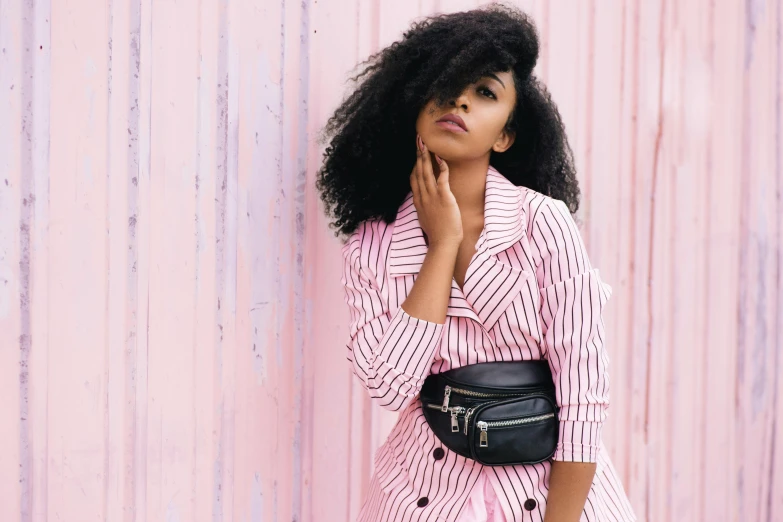 a woman posing in front of a pink wall