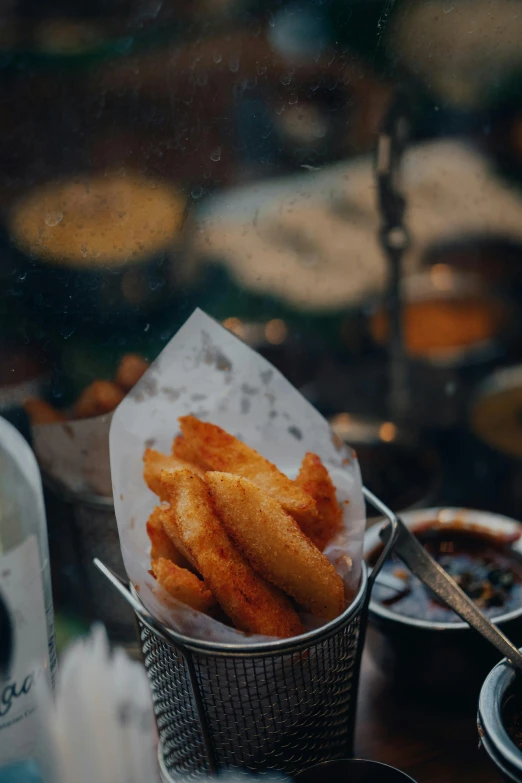 fish sticks in a basket with dipping sauce in the background