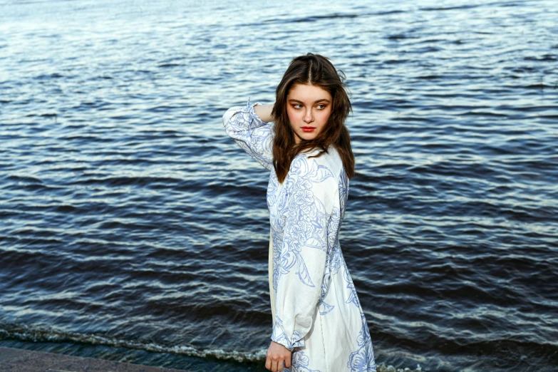 the girl standing next to the water is posing