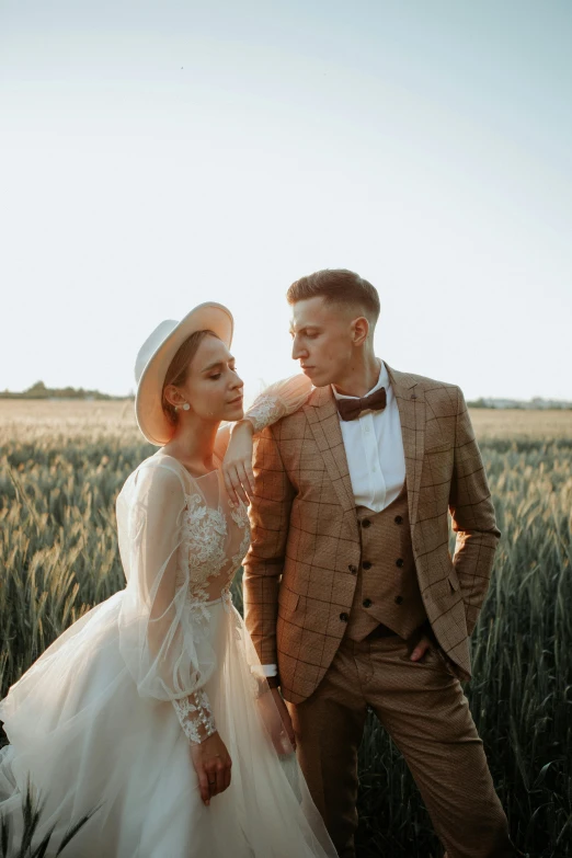 a man and woman wearing wedding attire are standing in a field