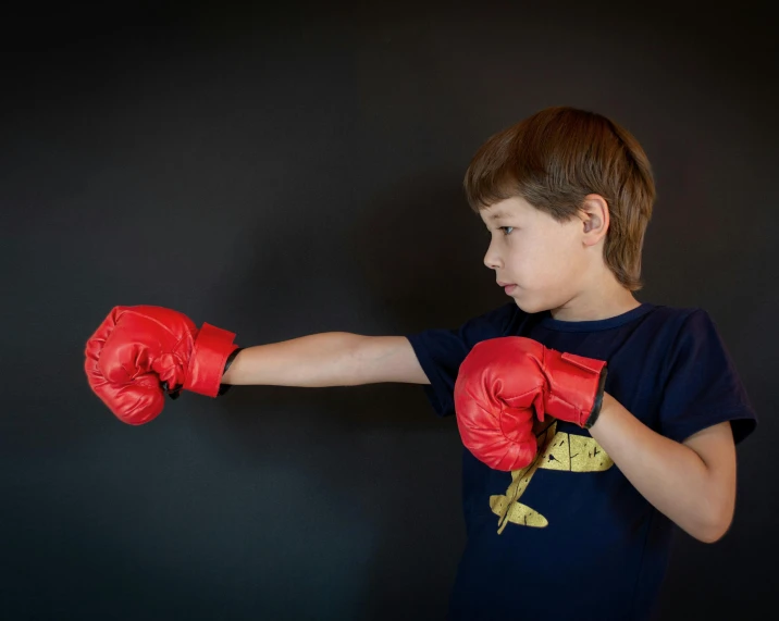 a little boy that is wearing boxing gloves