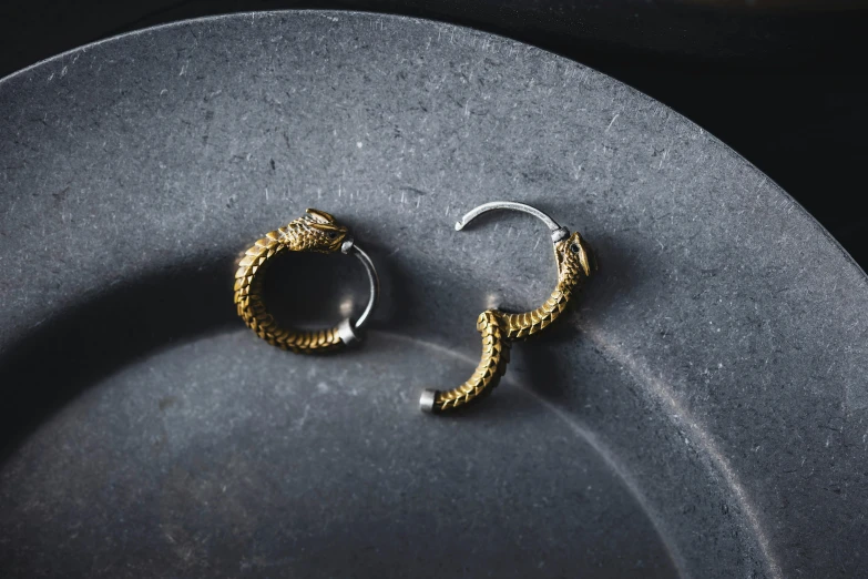 some very pretty shiny gold toned earrings on a plate