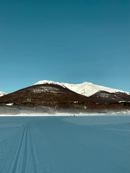 an expanse of snow in front of mountains on a sunny day