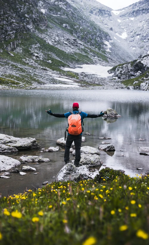 a man standing on a mountain and pointing out at the water